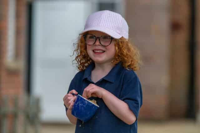 Nursery child playing with a cup of sand