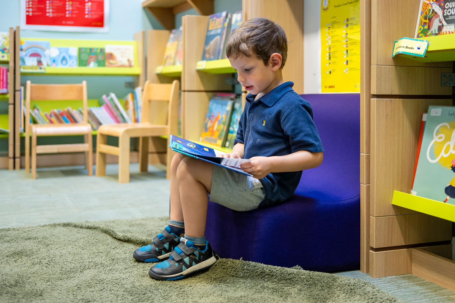Nursery child reading a book in a library