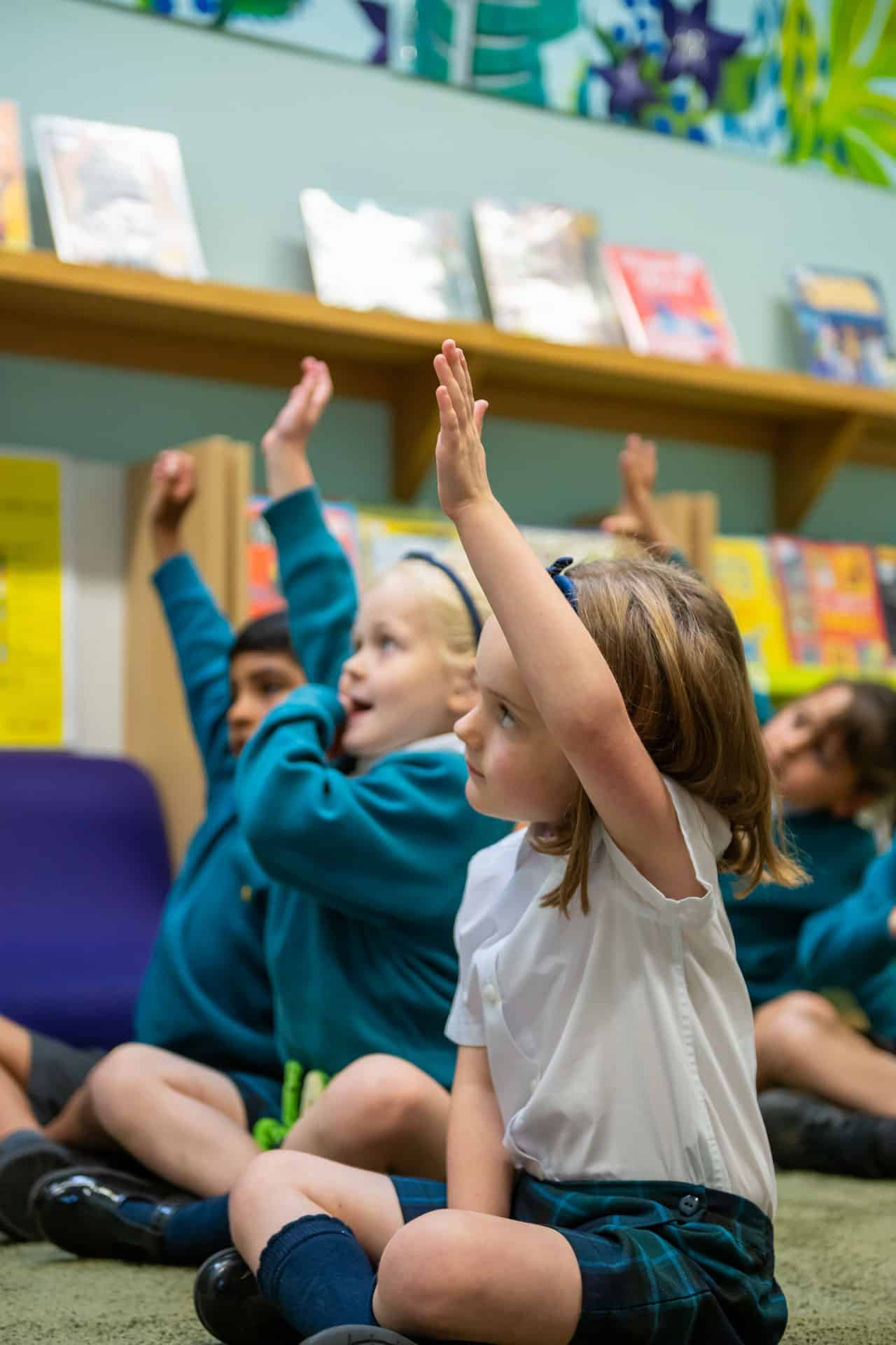 Children putting their hands up in a lesson