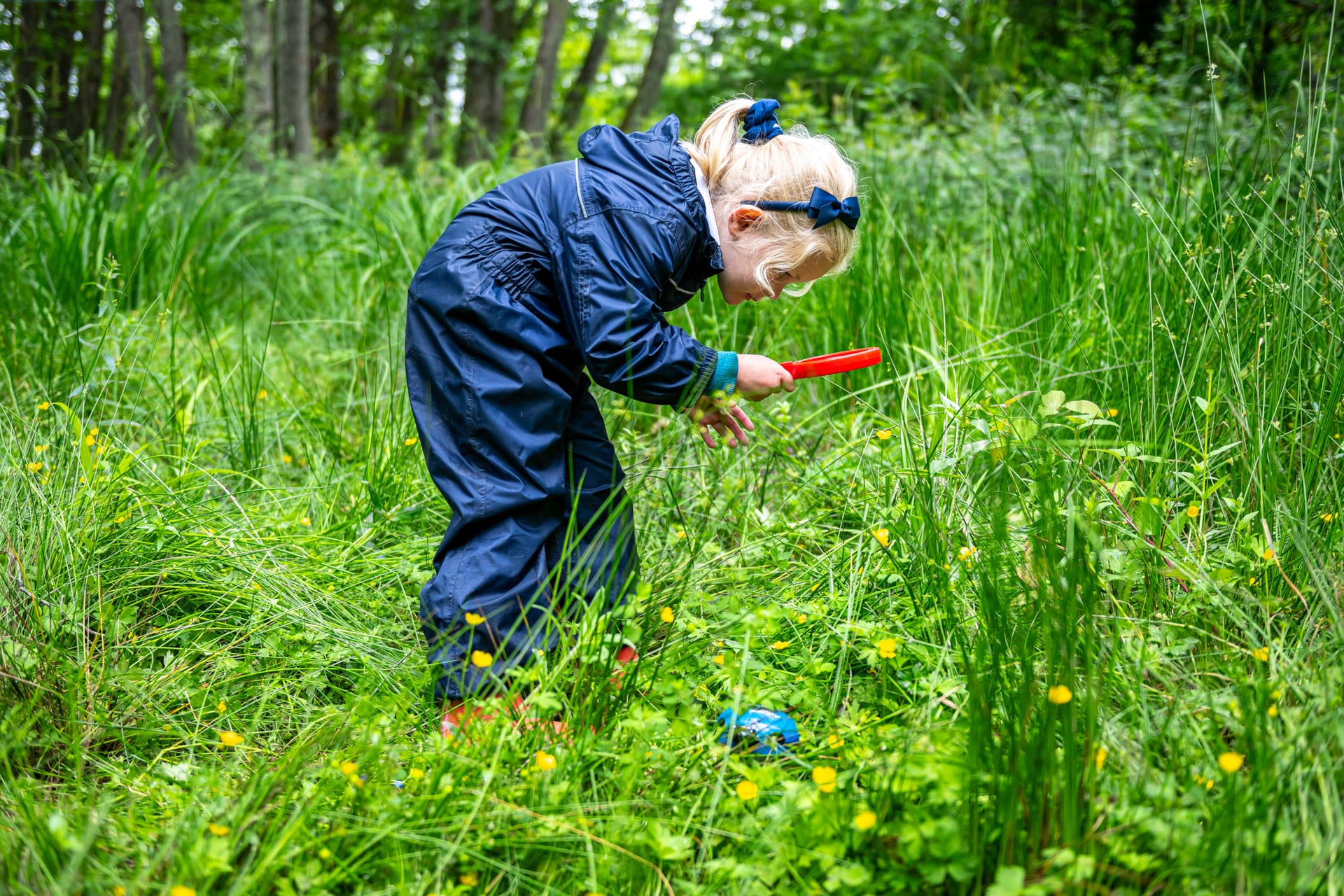 Prep children looking through a magnifying glass at forest school