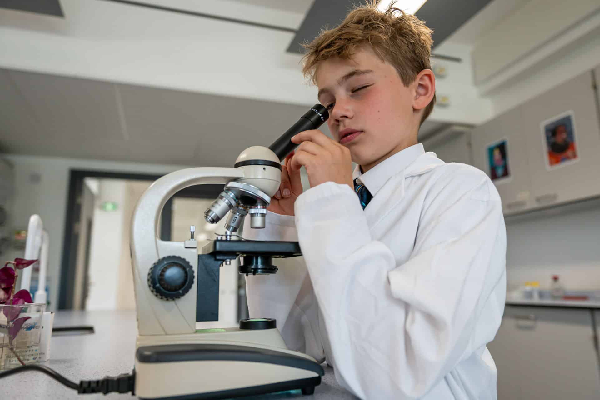 Boy looking in microscope in science lab