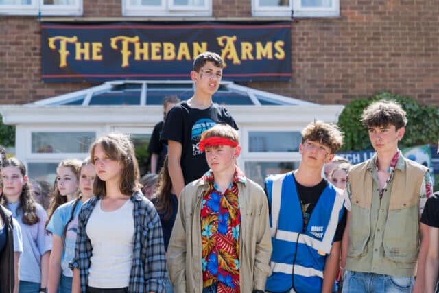 Cast members pose outside The Theban Arms, the pub set central to the storyline in the outdoor production of Antigone, summer 2025.