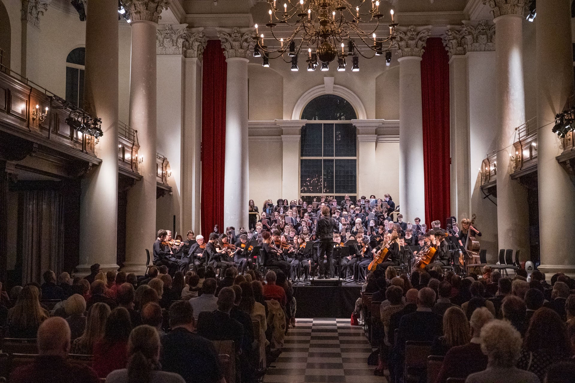 Choir and orchestra performing at Syphonia Square, viewed from the back of the hall.