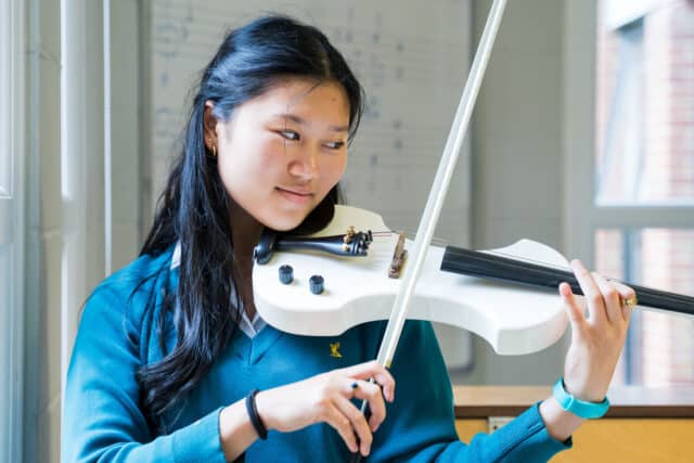 Female violinist practising in a music room at Ardingly.