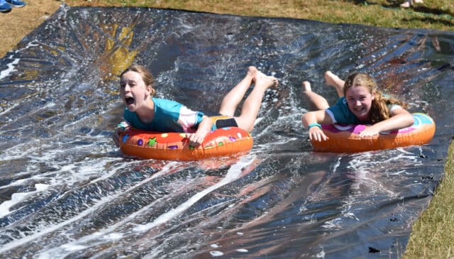 End of term fun, a couple of girls take to the slip and slide in rubber rings