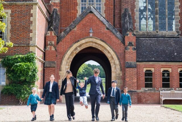 All aged children walking through the Archway with the oldest ones swinging a little girl from the Prep.