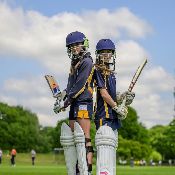 young female cricketers stand back to back