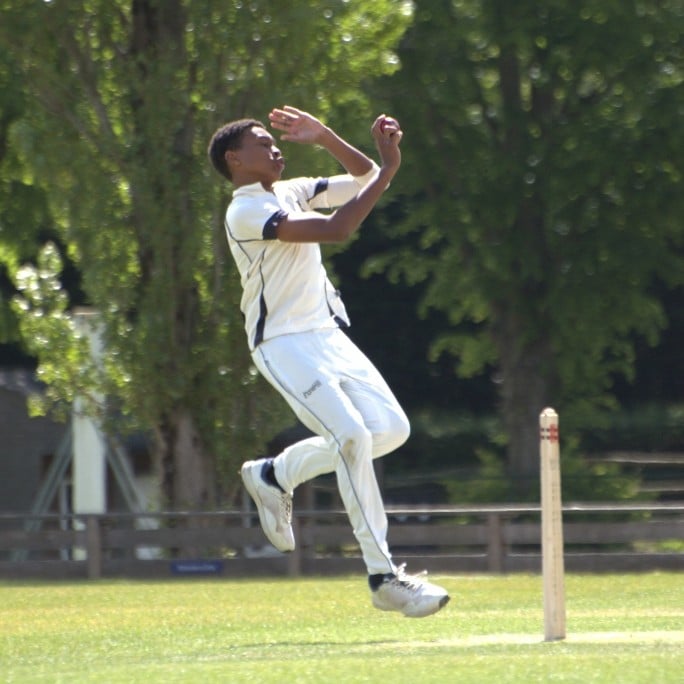 boy in whites bowling at cricket