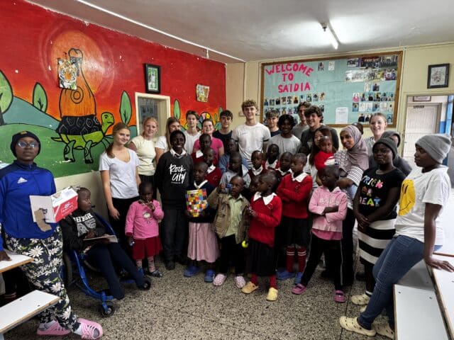 A group photo of students on their trip to Kenya in a classroom